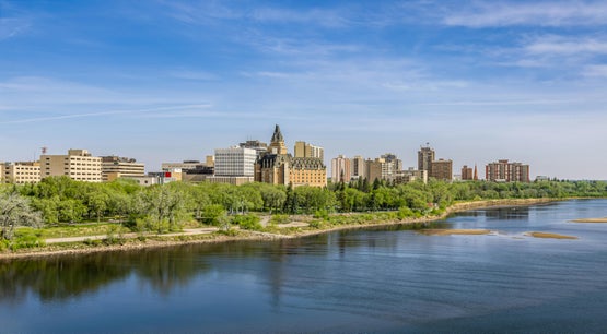 Downtown Saskatoon skyline with Delta Bessborough hotel and riverbank park along the South Saskatchewan River in spring