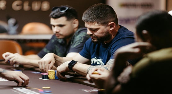 Players sitting at a casino poker table with chips during a game