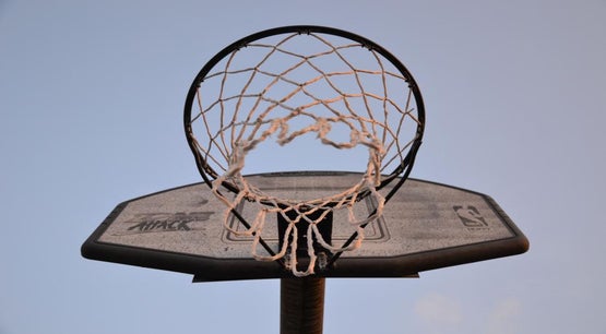 Close‑up view of a basketball hoop and backboard with net against clear sky, featuring NBA logo and “Zone Attack” branding