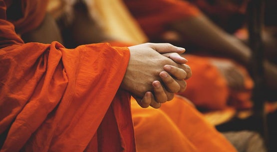 Buddhist Monk in Orange Robes Buddhist monk in orange robes sitting with clasped hands