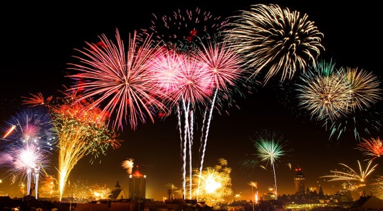 Colorful fireworks bursting over a city skyline at night during a large outdoor celebration