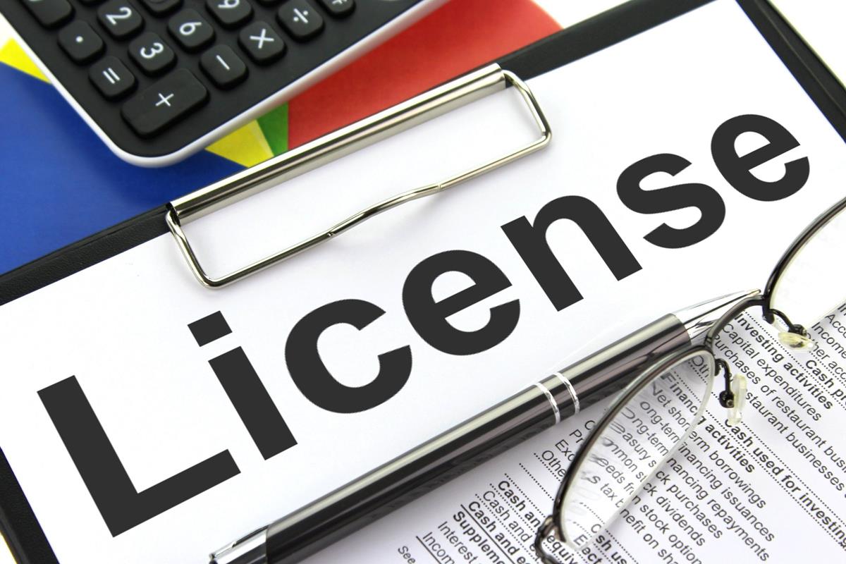 Octoplay Gets Conditional AGLC Approval for Alberta Clipboard with a "License" document, calculator, pen, and glasses, symbolizing Octoplay's conditional AGLC approval in Alberta