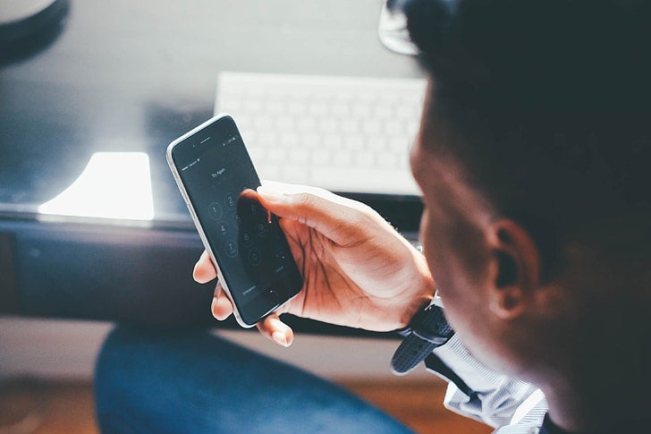 Man entering a passcode on his smartphone, representing online gambling and iGaming activity in Alberta