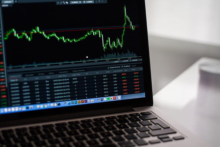 Ontario Sports Betting Drops 30% in August, Casino Soars Laptop screen showing a green financial chart with sharp swings and a trading data table below